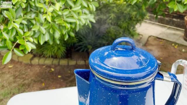 Steam coming out of the spout of the Stansport Enamel 8-Cup Percolator outdoors.
