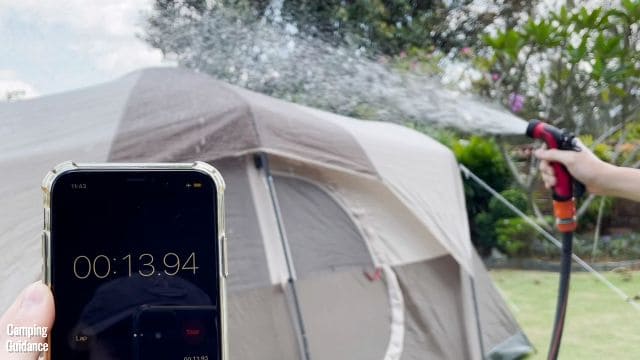 This is a picture of me conducting a rain test on the WeatherMaster 10-Person Tent by using a stopwatch and a water hose.