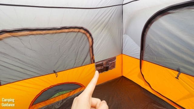 This is a picture of me pointing to the bigger pocket (10 by 19 inches) of the Core 10-Person Straight Wall Cabin Tent.