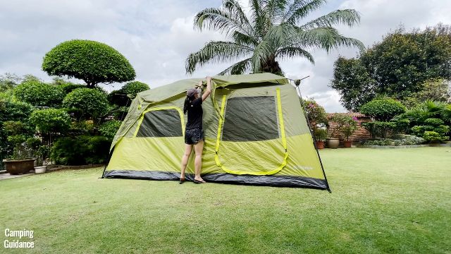 This is a picture of me draping the rainfly of the Outdoor Products 10-Person Instant Cabin Tent above the tent to secure it in place.