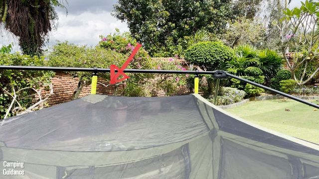 This is a picture of the top of the Outdoor Products 10-Person Instant Cabin Tent. The red arrow is pointing towards one of the pre-attached pole clips, which is connected to one of the pre-attached steel poles.