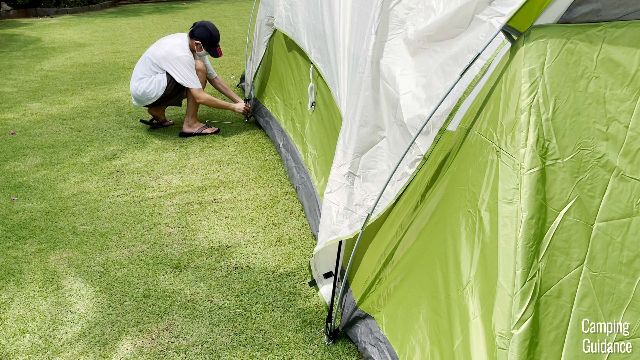 This is a picture of my brother securing the S-hooks of the rainfly to the tent body, at the back of the Coleman Montana 8-Person Tent.